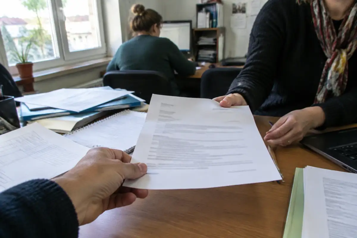 Main présentant une feuille imprimée illisible de l'autre côté d'un bureau